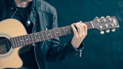 Mand i sort skindjakke spiller akustisk guitar